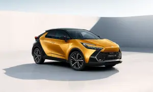 Nowy Toyota C-HR Hybrid w kolorze złotym, z czarnym dachem i felgami, prezentuje się nowocześnie na tle białej ściany.