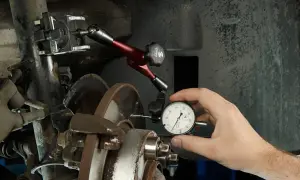 Mechanik mierzy bicie tarczy hamulcowej, by zdiagnozować drgania kierownicy przy hamowaniu z dużej prędkości.