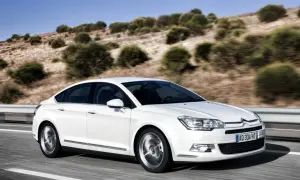 Biały Citroen C5 z hydropneumatycznym zawieszeniem jedzie po drodze. Zastanawiasz się nad citroen c5 zawieszenie hydropneumatyczne koszt naprawy?