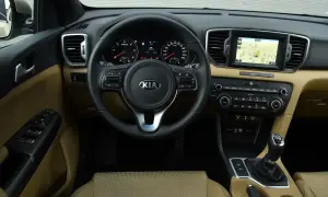Wnętrze Kia Sportage IV z beżową tapicerką, multimediami z nawigacją i wielofunkcyjną kierownicą.