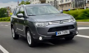 Szary Mitsubishi Outlander 3 jedzie po miejskiej drodze.