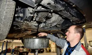 Mechanik spuszcza stary olej z silnika, przypominając o regularnej wymianie oleju dla sprawnego działania auta.