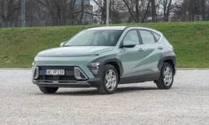 Nowy Hyundai Kona 1.6 benzyna w pastelowym kolorze, zaparkowany na żwirowym placu, gotowy na miejskie przygody.