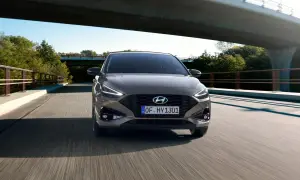 Nowy Hyundai i30 2023 w kolorze brązowym jedzie po moście wśród zieleni.