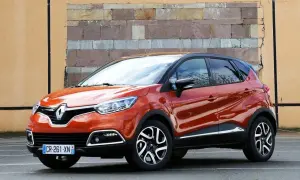Pomarańczowy Renault Captur 2016 z czarnym dachem stoi przed ceglaną ścianą.