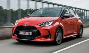Czerwony Toyota Yaris 1. generacji z czarnym dachem pędzi po drodze.