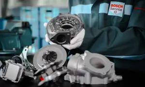 Mechanik w fartuchu Bosch Service prezentuje części turbosprężarki, potencjalnie związane z błędem dtc p0299 renault.
