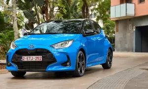 Błękitna Toyota Yaris 1.3 benzyna zaparkowana na tle zieleni i budynku. Zastanawiasz się, jaki olej do toyoty yaris 1.3 benzyna?