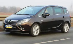 Ciemnobrązowy Opel Zafira Tourer 1.4 Turbo na drodze. Kierowca za kierownicą.