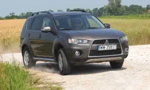 Brązowy Mitsubishi Outlander 2008 na drodze polnej, w tle pole zboża.