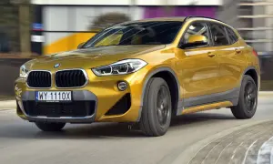 Złoty BMW F39 w ruchu, z widocznym grillem i reflektorami.