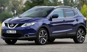 Granatowy Nissan Qashqai J11 z chromowanymi relingami dachowymi i felgami stoi na drodze.