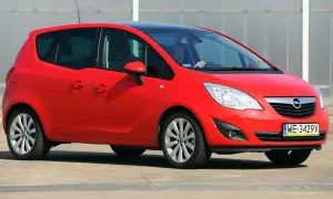 Czerwony Opel Meriva 1.6 benzyna z czarnym dachem, zaparkowany na zewnątrz. Kierowca w okularach siedzi za kierownicą.