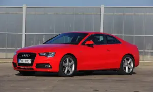 Czerwone Audi S5 z 2014 roku, sportowe coupe z elegancką linią, zaparkowane przed nowoczesnym budynkiem.
