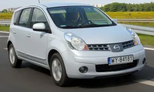 Srebrny Nissan Note E11 jedzie po drodze, za kierownicą siedzi mężczyzna.