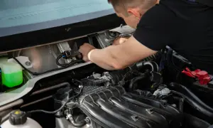 Mechanik pracuje przy silniku, podłączając przewody. Widać zbiornik płynu i elementy p0010.