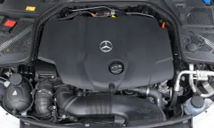 Silnik w Mercedesie C W205. Widoczna czarna osłona z logo producenta, przewody i elementy układu dolotowego.