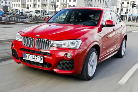 Czerwone BMW X4 w ruchu miejskim. Wady tego modelu to m.in. ograniczona widoczność z tyłu i wysoka cena.
