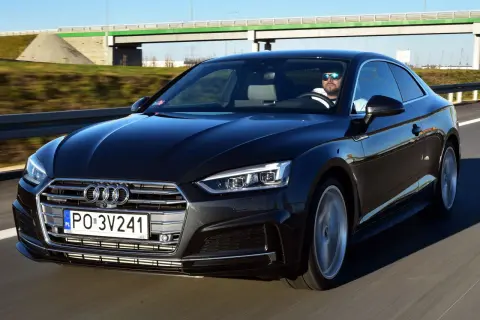 Czarny Audi A5 F5 z kierowcą w okularach przeciwsłonecznych jedzie autostradą.