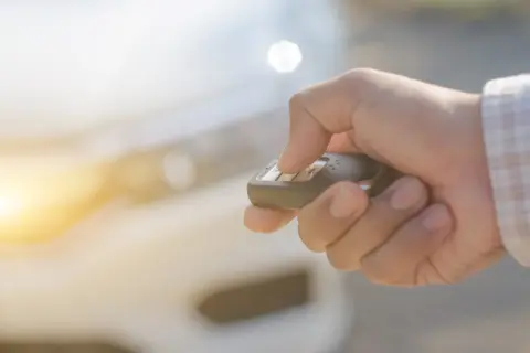 Dłoń naciska przycisk kluczyka samochodowego, aktywując immobilizer.