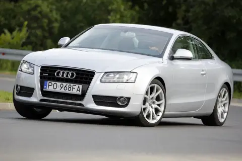 Srebrne Audi A5 z 2006 roku na drodze, z widocznym kierowcą.