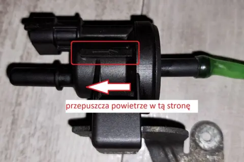 Zawór podciśnienia, potencjalna przyczyna DTC P0172 w Volkswagen. Strzałka wskazuje kierunek przepływu powietrza.