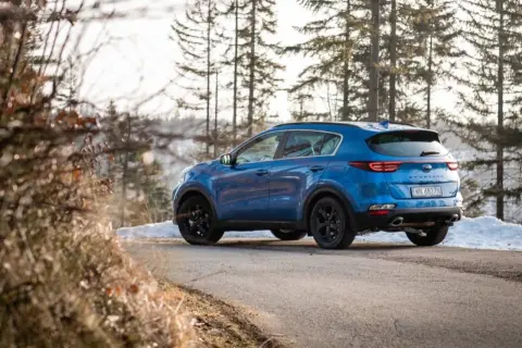 Niebieski Kia Sportage 3 na zimowej drodze. Zastanawiasz się, jakie opony do Kia Sportage 3 będą najlepsze?