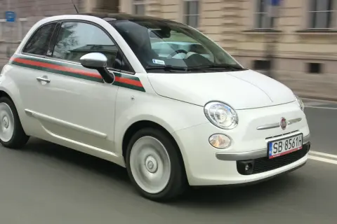 Biały Fiat 500 1.2 z zielono-czerwonym pasem na boku, w ruchu miejskim.