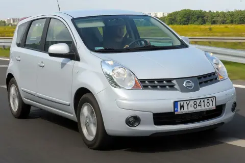 Srebrny Nissan Note E11 jedzie po drodze, za kierownicą siedzi mężczyzna.