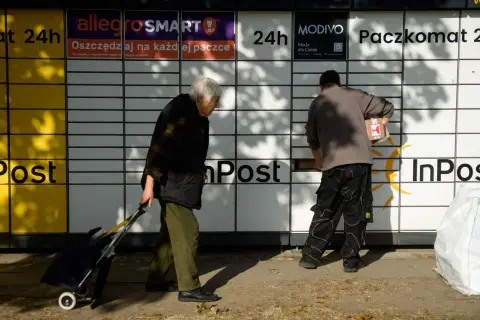 Osoby korzystają z paczkomatu InPost. Zastanawiasz się, ile prądu zużywa paczkomat? To urządzenie jest energooszczędne.