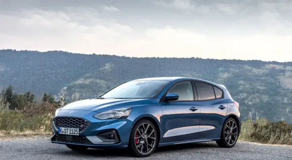 Niebieski Ford Focus MK3 ST na tle gór. Zwróć uwagę na sportowe felgi i opony, które podkreślają jego dynamikę.