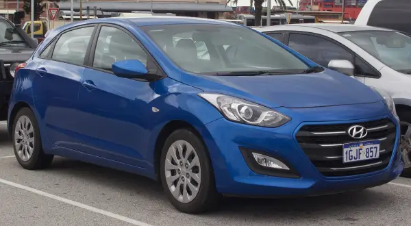 Niebieski Hyundai i30 na parkingu. Widoczne felgi i opony, które sugerują standardowy rozmiar dla tego modelu.