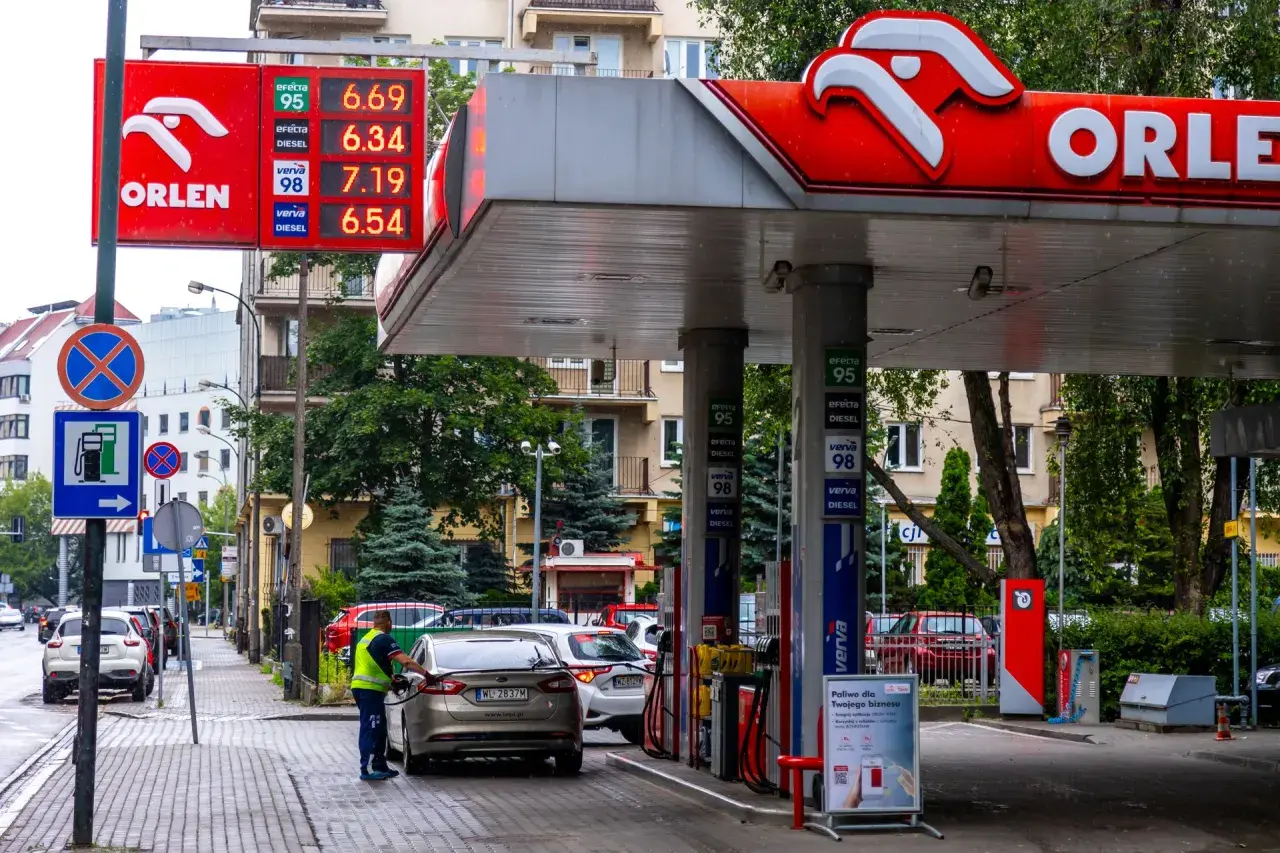 Na stacji paliw ORLEN, która jest polska, tankowany jest samochód. Ceny paliw widoczne na wyświetlaczu.