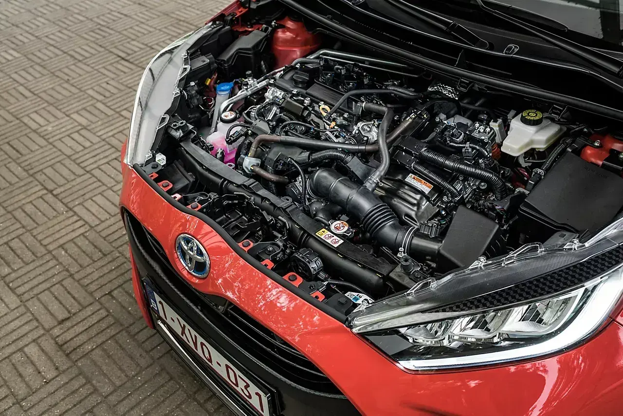 Silnik Toyoty Yaris 1.0. Widok komory silnika z widocznym zbiorniczkiem płynu chłodniczego i innymi elementami.