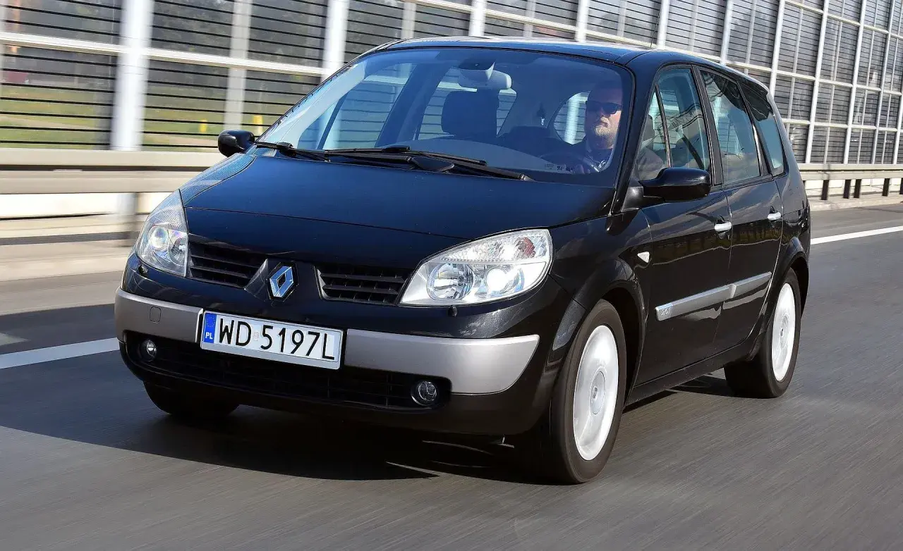 Czarny Renault Scenic 2 1.6 16v na drodze. Kierowca w okularach przeciwsłonecznych.