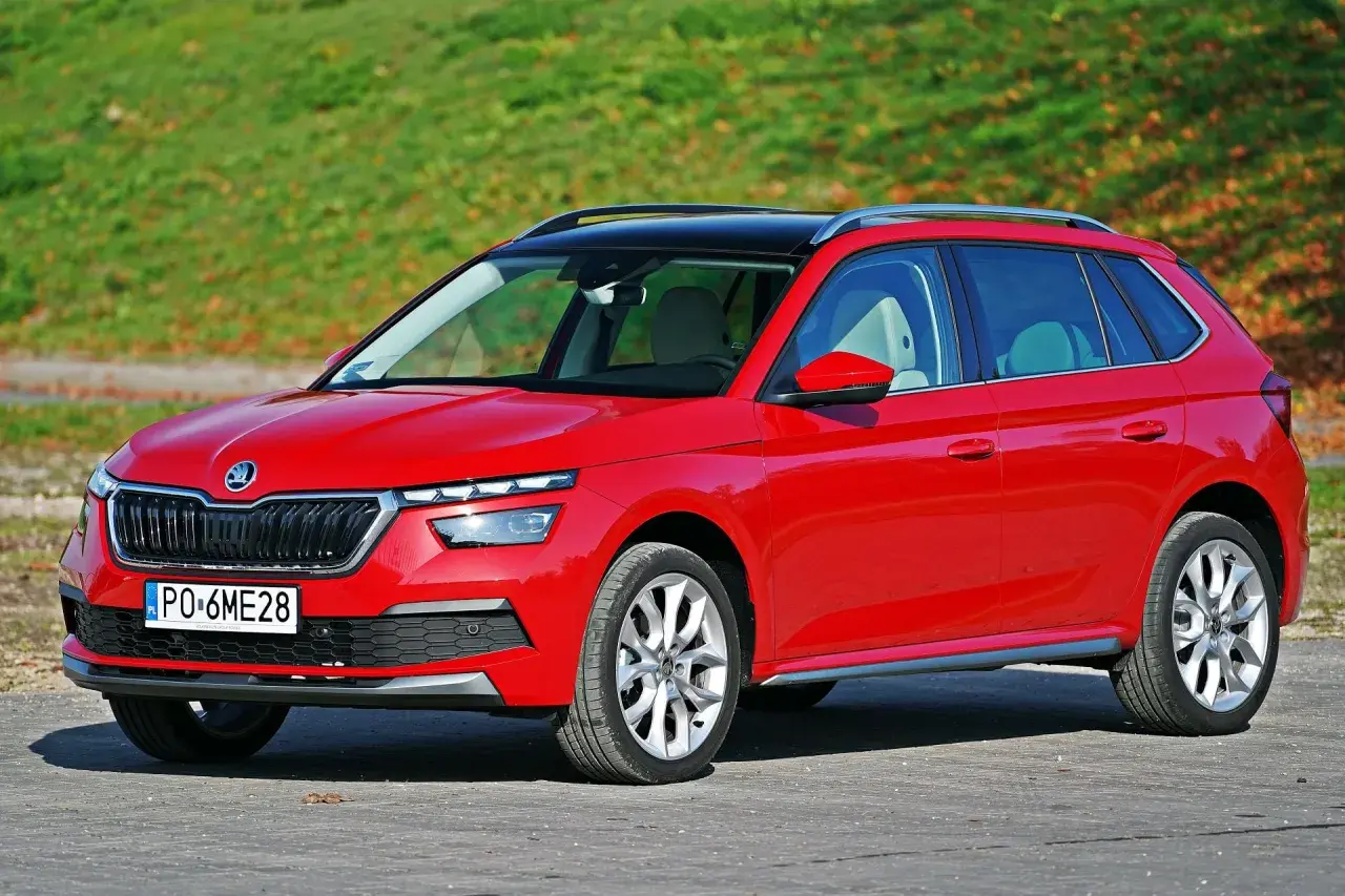 Czerwona Skoda Kamiq na tle zieleni. Zwróć uwagę na jej kompaktowe skoda kamiq wymiary, idealne do miasta.