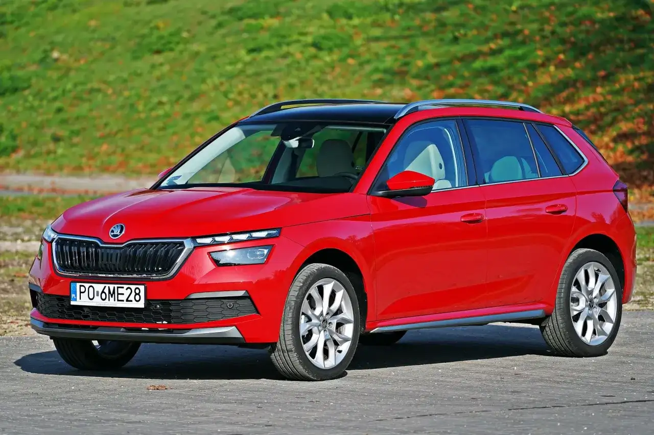 Czerwona Skoda Kamiq na tle zieleni. Zwróć uwagę na jej kompaktowe skoda kamiq wymiary, idealne do miasta.