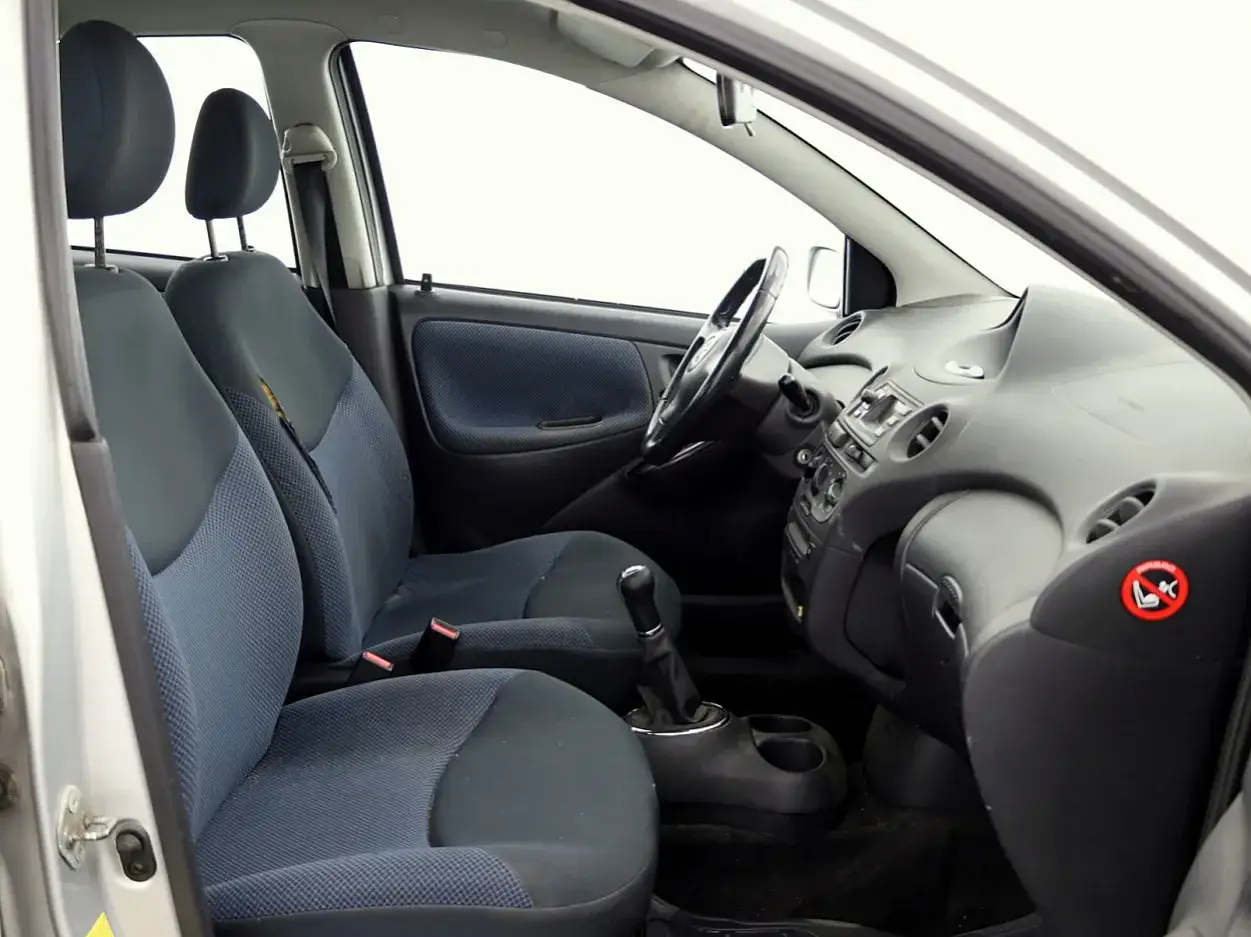 Wnętrze Toyoty Yaris 1. Widoczne przednie fotele, kierownica i deska rozdzielcza.