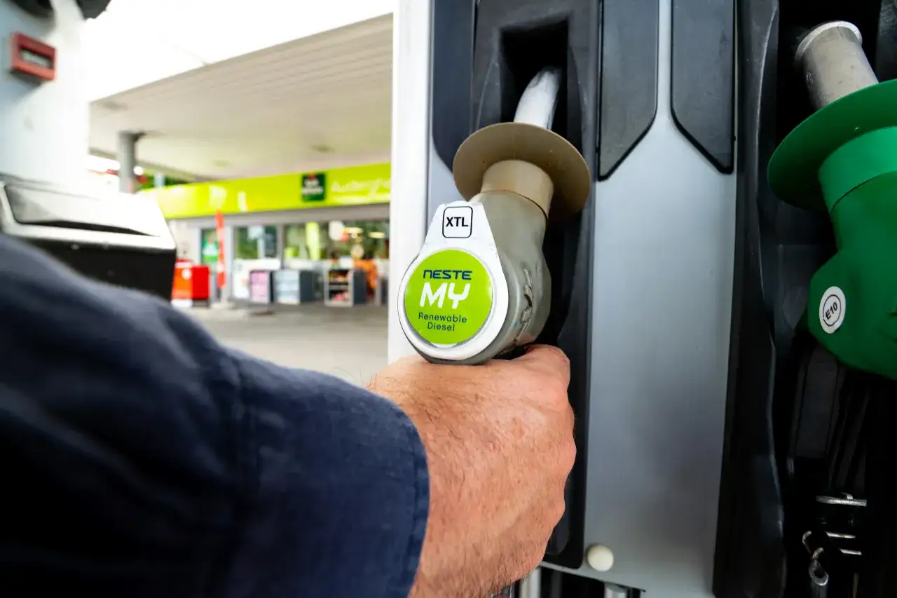 Dłoń trzymająca dystrybutor z napisem Neste MY Renewable Diesel, oznaczenie XTL. Tankowanie ekologicznego paliwa.