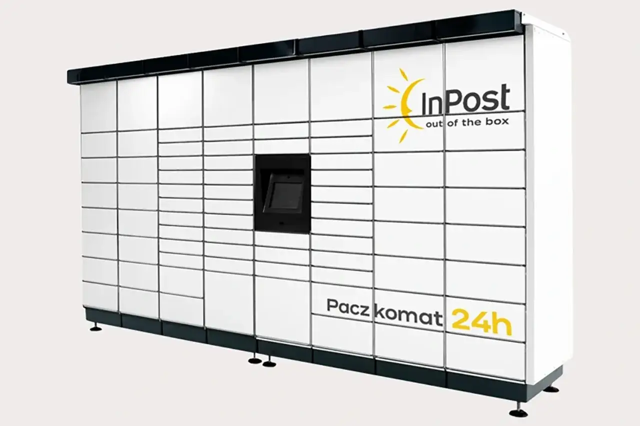 Biały Paczkomat InPost z panelem do obsługi i licznymi schowkami. Idealny do nadawania i odbierania paczek, nawet w nocy.