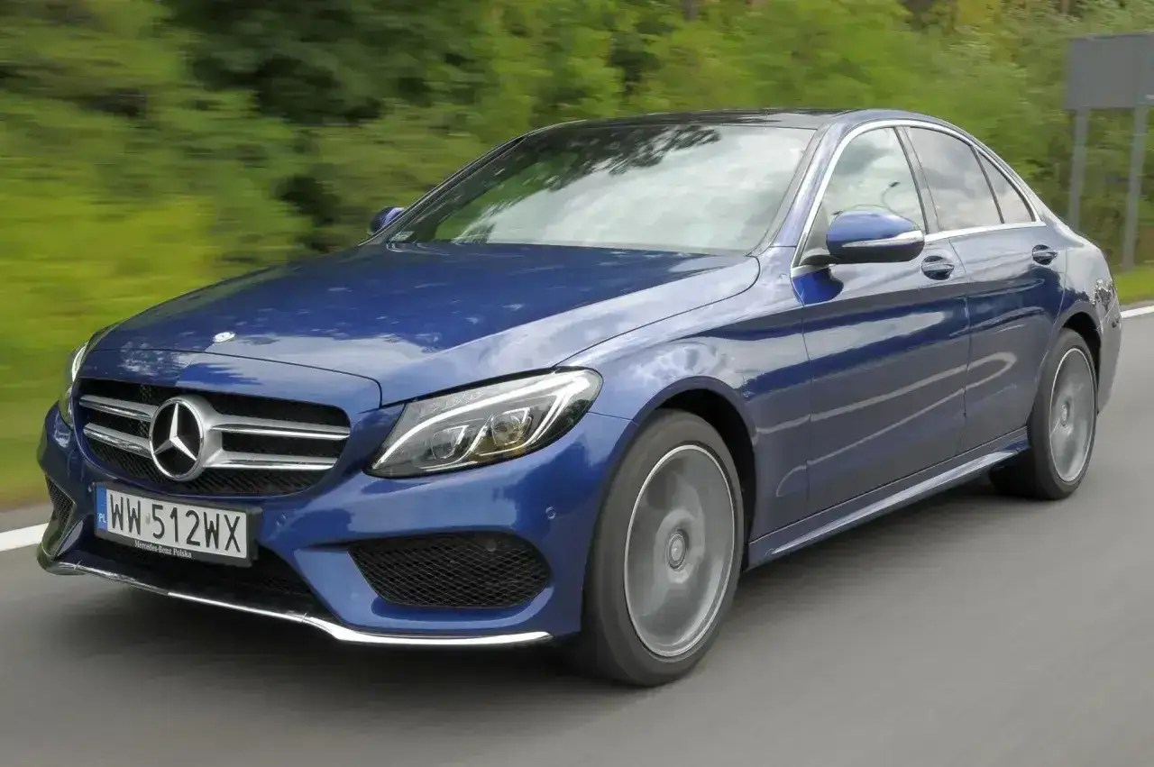 Elegancki, granatowy Mercedes C W205 w ruchu, z rozmytym tłem zieleni i drogi.
