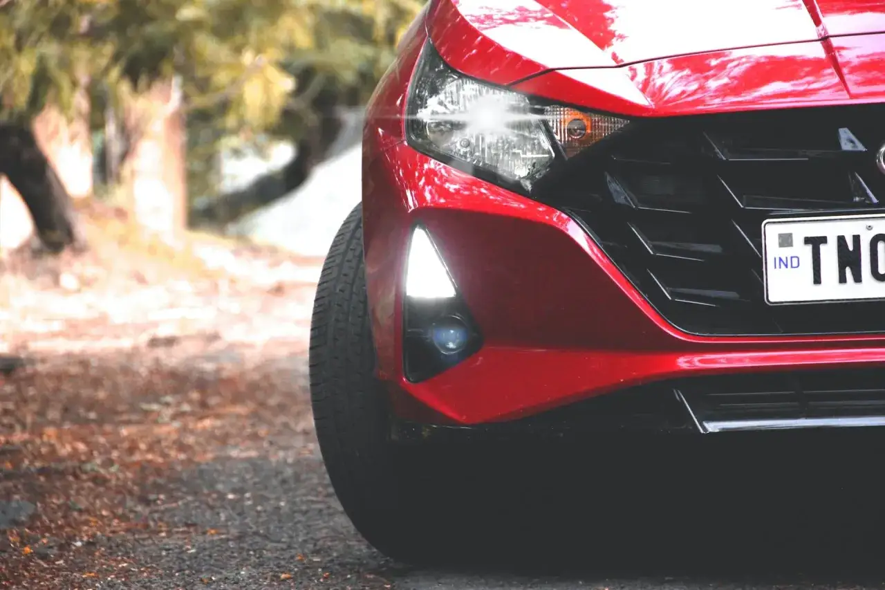 Czerwony Hyundai i20 z włączonymi światłami przeciwmgielnymi przednimi, gotowy na mglistą drogę.