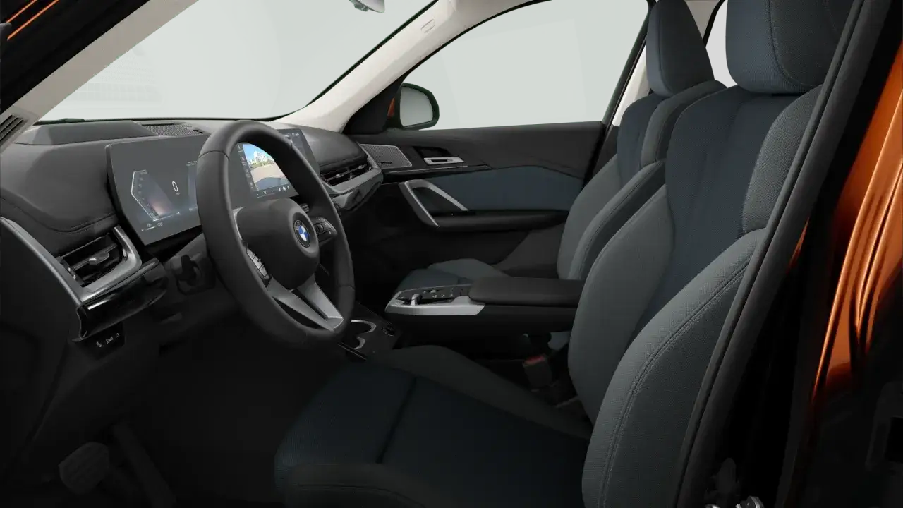 Wnętrze BMW X1 2020 z cyfrowymi zegarami, ekranem multimediów i wygodnymi, tapicerowanymi siedzeniami.