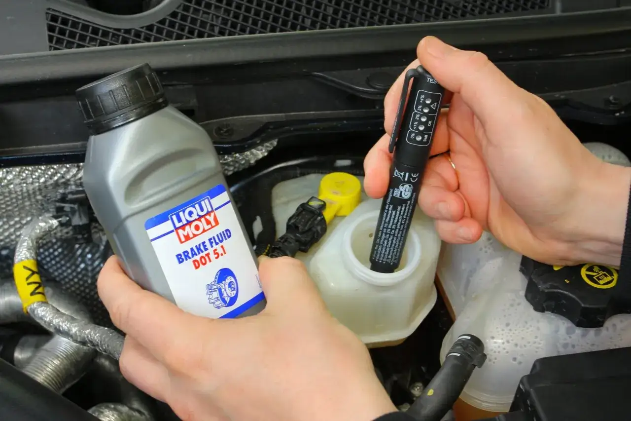 Sprawdzanie płynu hamulcowego DOT 5.1 w Golfie 4. Tester zanurzony w zbiorniczku, obok butelka Liqui Moly.