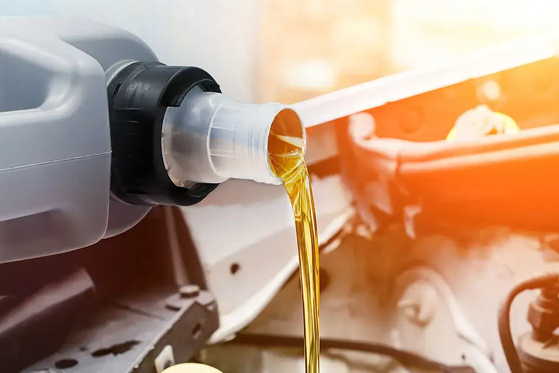 mechanik samochodowy prezentujący dwa różne oleje silnikowe
