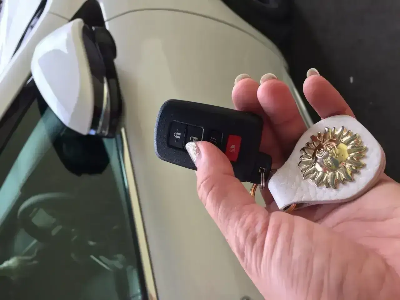 Dłoń trzyma kluczyk samochodowy z przyciskami. W kluczyku jest immobilizer, który chroni auto.