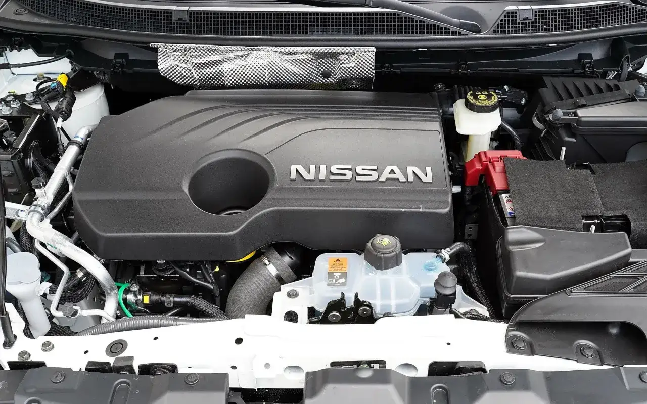 Silnik Nissan Qashqai J11 z widocznym logo NISSAN na czarnej osłonie. Widać akumulator i płyny eksploatacyjne.