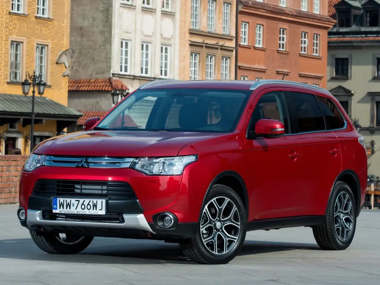Czerwony Mitsubishi Outlander 3 na tle zabytkowych kamienic.