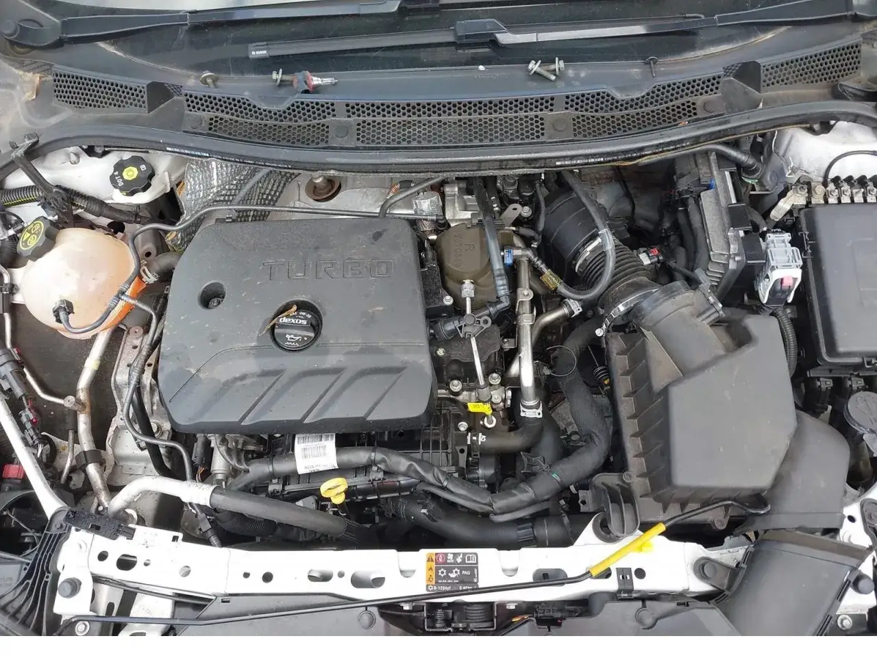 Silnik 1.4 Turbo w Opel Astra K. Widoczny jest czarny plastikowy dekiel z napisem 