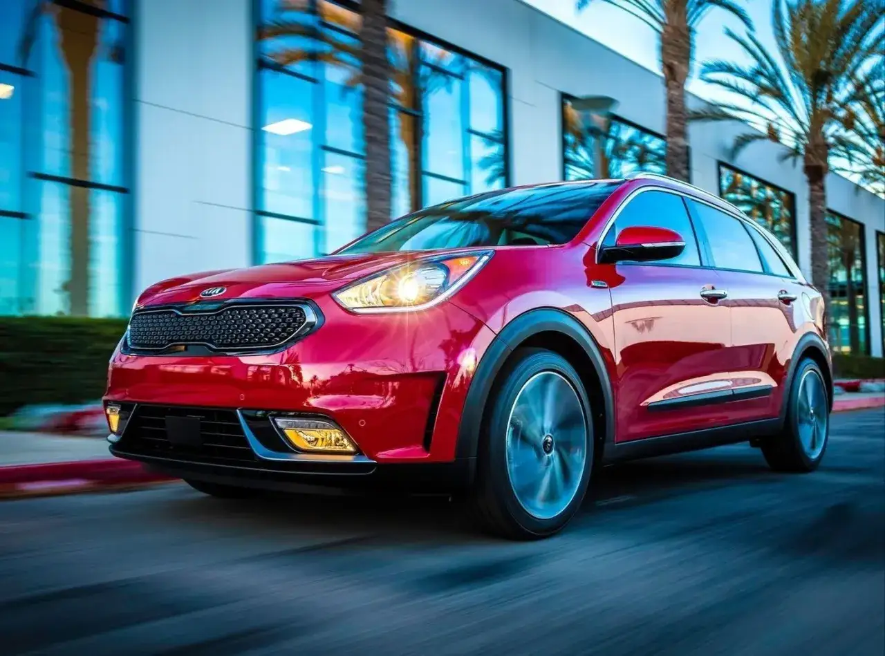 Czerwone Kia Niro w ruchu, z widocznymi światłami i felgami. Choć auto wygląda świetnie, warto pamiętać o jego potencjalnych wadach.